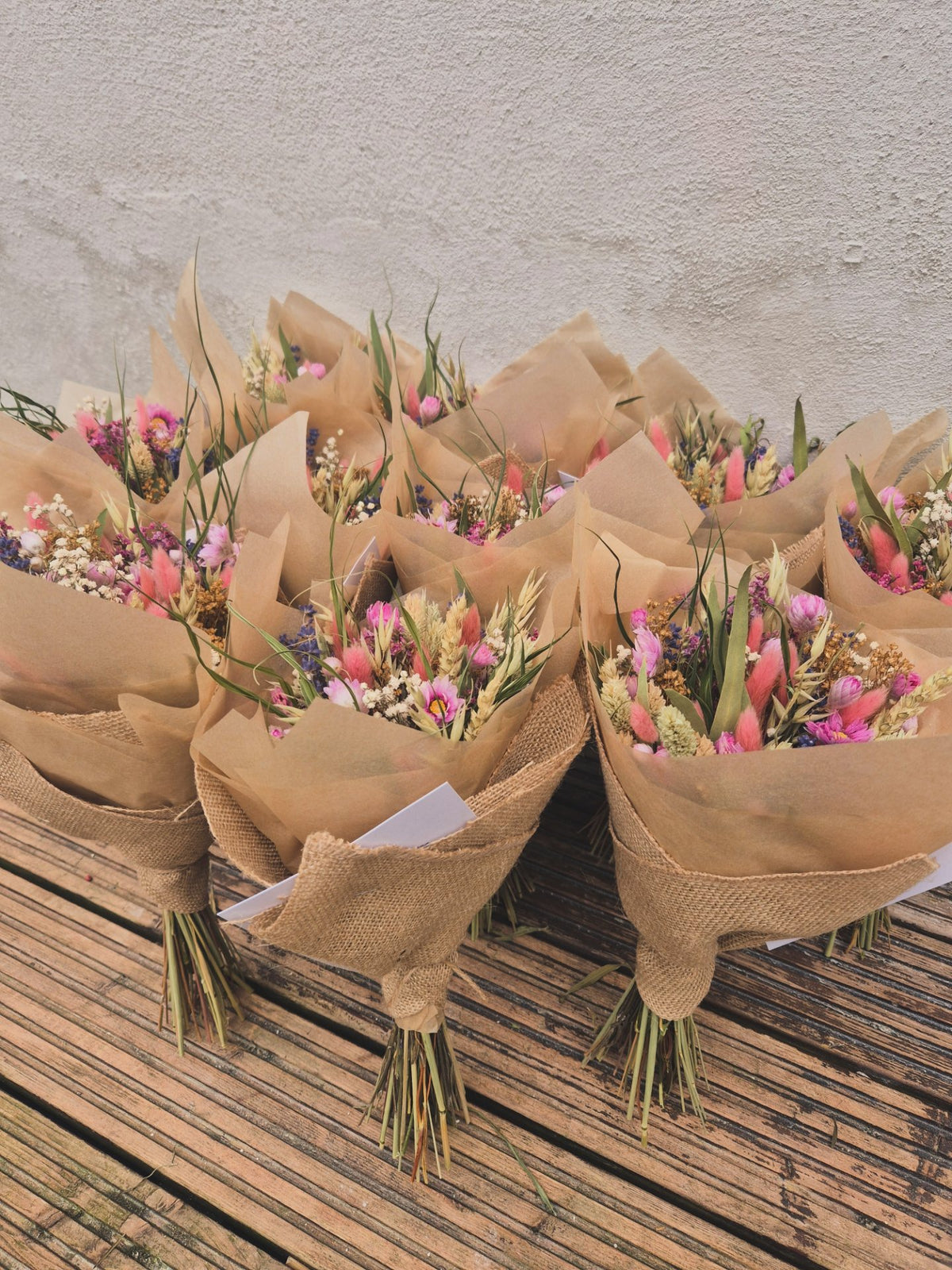 A sea of dried flower bouquets wrapped in brown paper on a wooden surface.