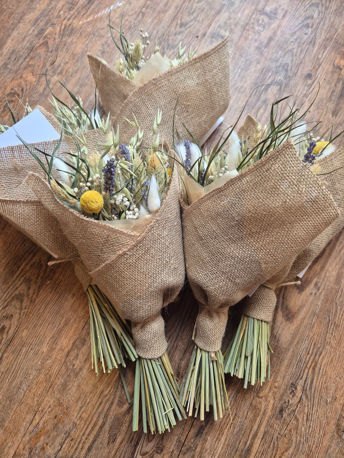 Bouquets of dried flowers wrapped in hessian on a wooden surface