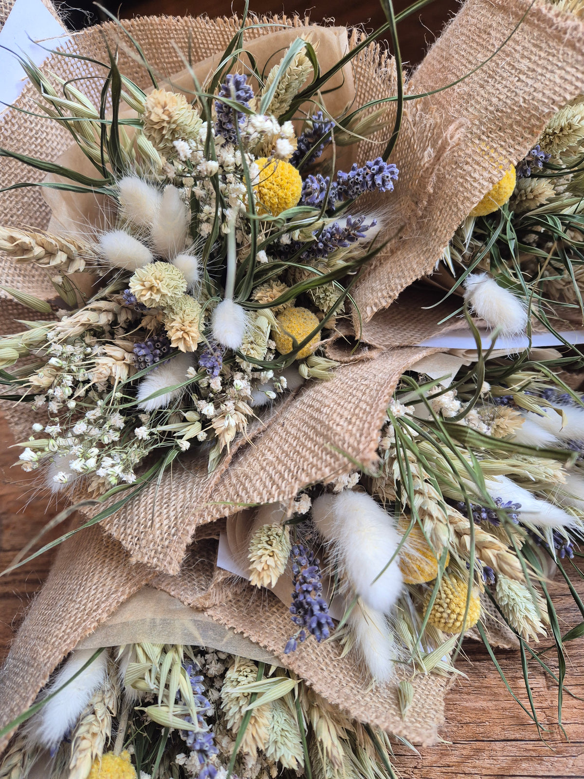 Dried flower bouquets featuring yellow, white and blue hues and wrapped in a hessian wrap.