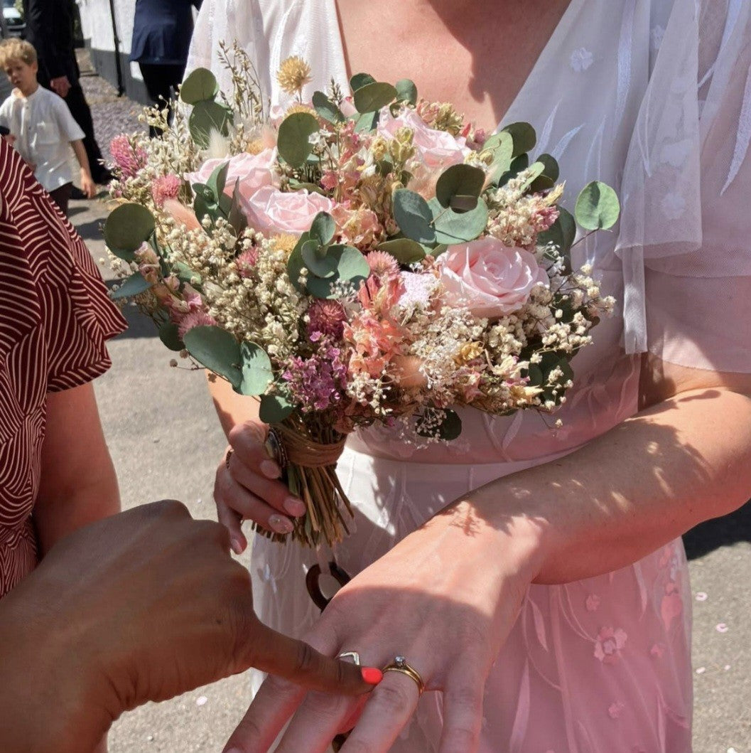 A large dried floral brides bouquet with pink roses, eucalyptus, and gypsophila. 