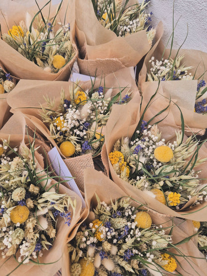 A big selection of bouquets of dried flowers wrapped in brown paper on a textured surface