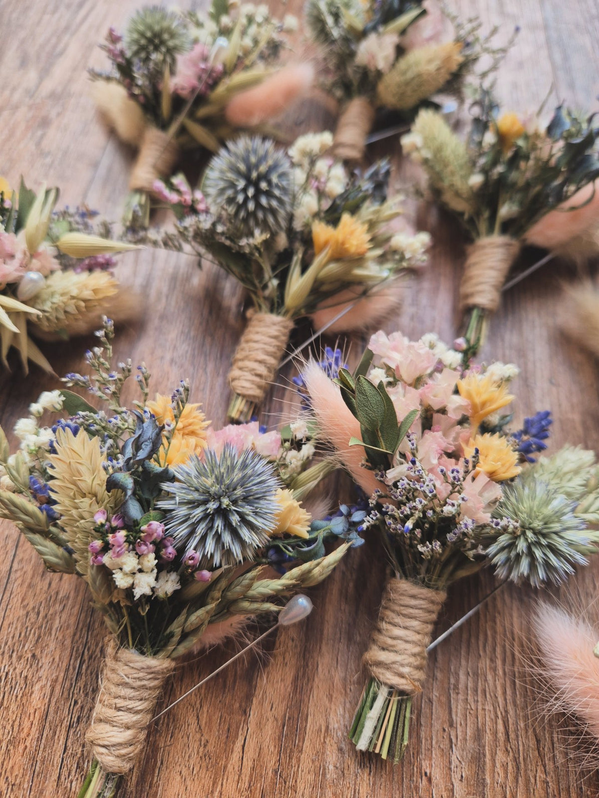 A stunning collection of dried flower buttonholes from groomsmen on a wooden surface