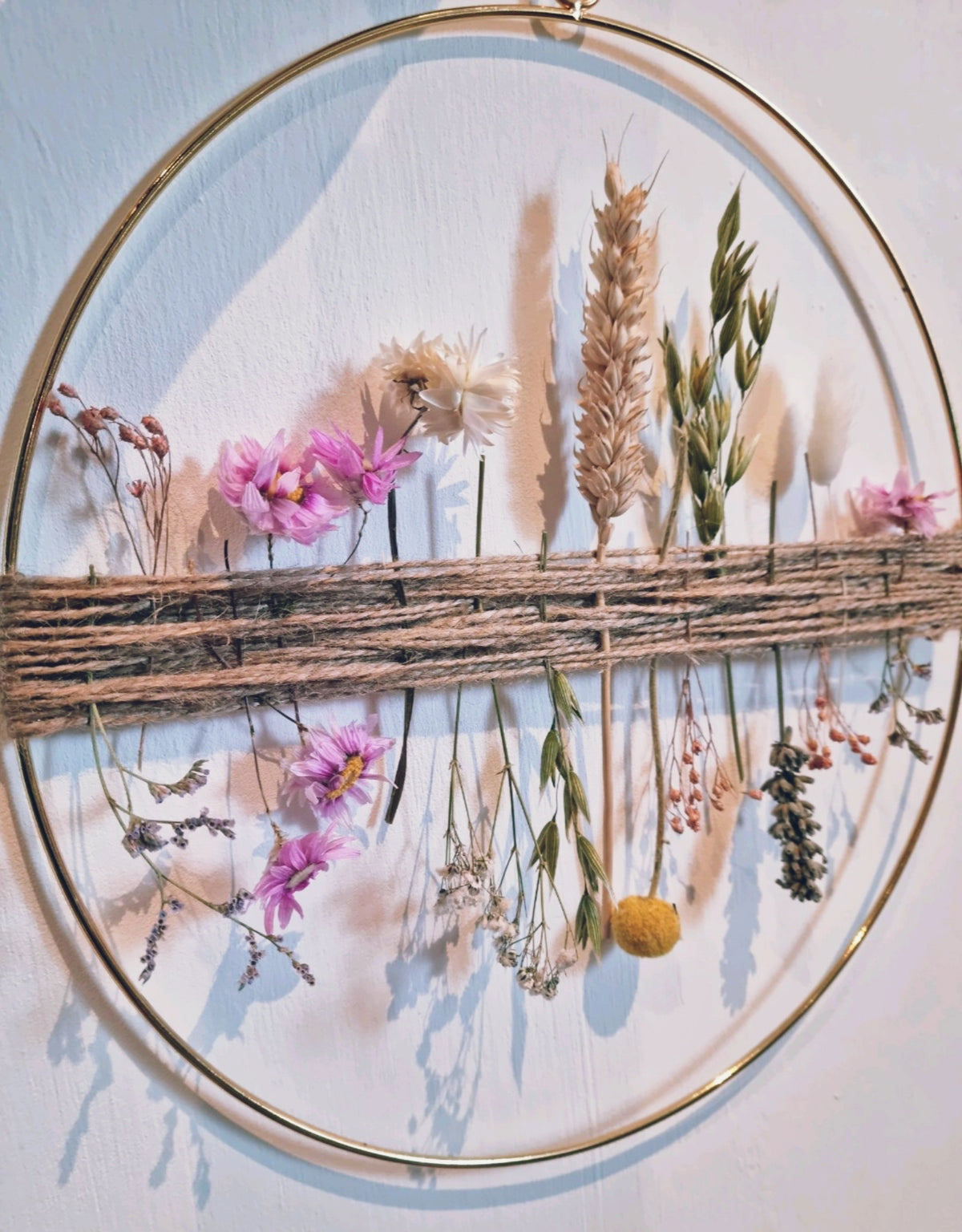 A gold hoop with pink and white dried flowers 