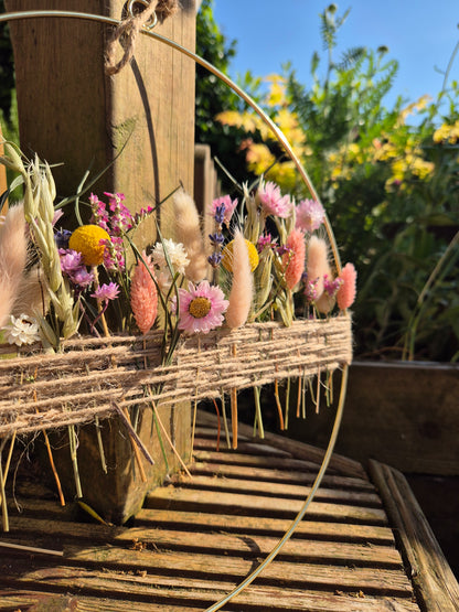 A summer inspired bright and colourful dried flower hoop pictured in a summer garden