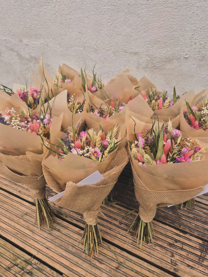 A sea of dried flower bouquets wrapped in brown paper on a wooden surface.