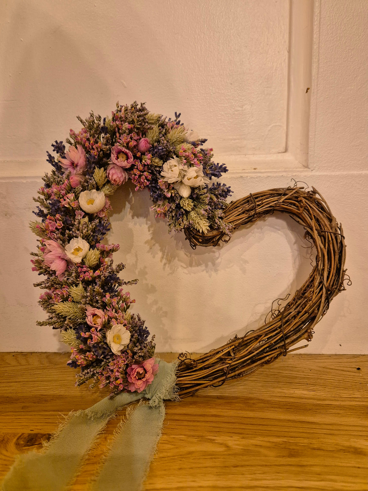 Dried flower heart shaped wreath decorated to one side and finished with chiffon, sage ribbon