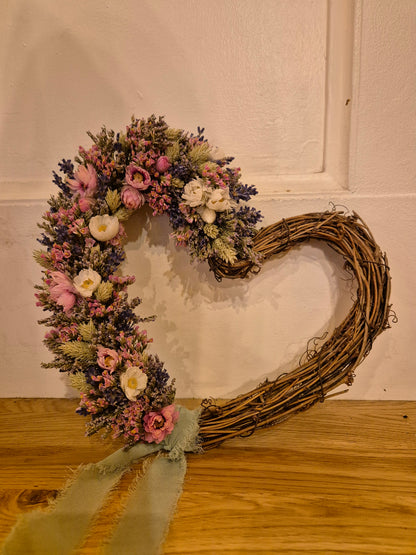 Dried flower heart shaped wreath decorated to one side and finished with chiffon, sage ribbon