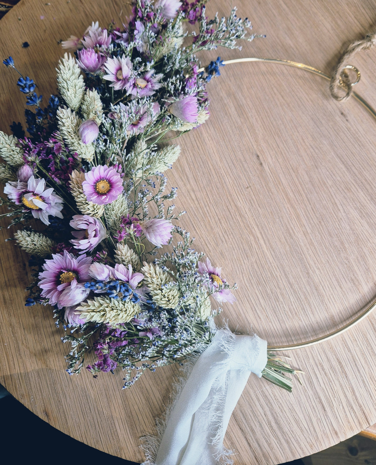 Dried flower wreath on a wooden surface with a old hoop and chiffon cream ribbon