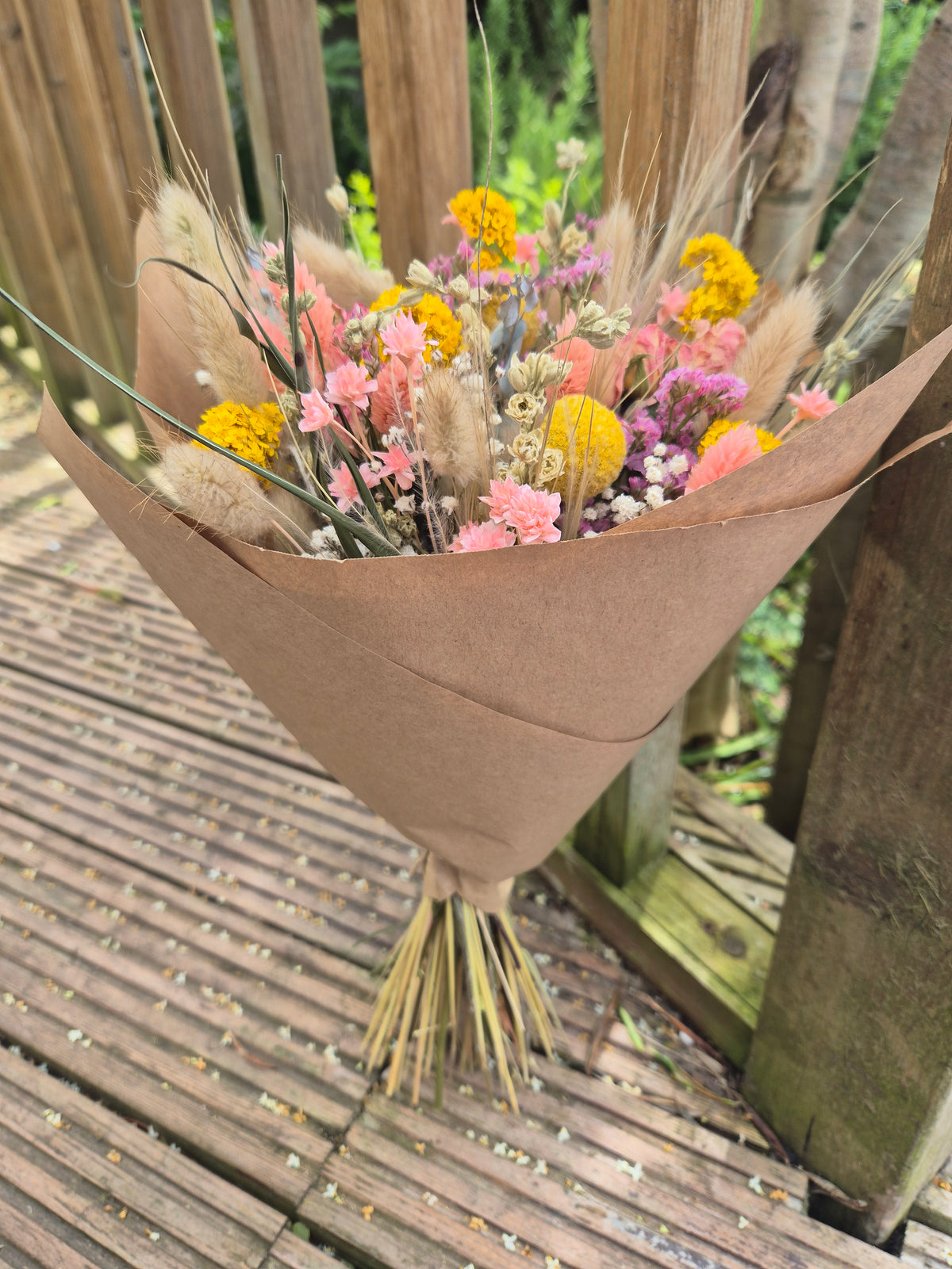 Bouquet of flowers in a brown paper cone on a wooden surface