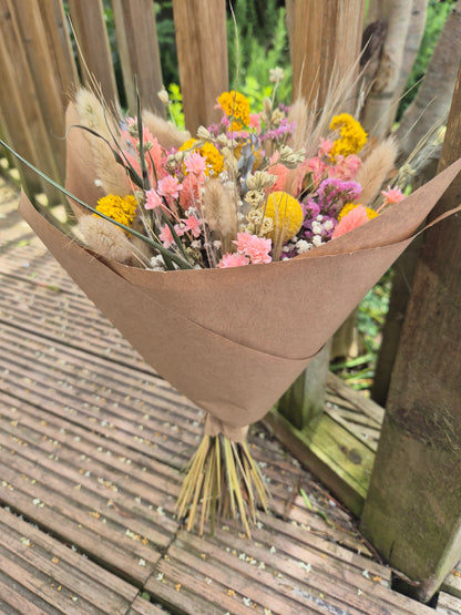 Bouquet of flowers in a brown paper cone on a wooden surface