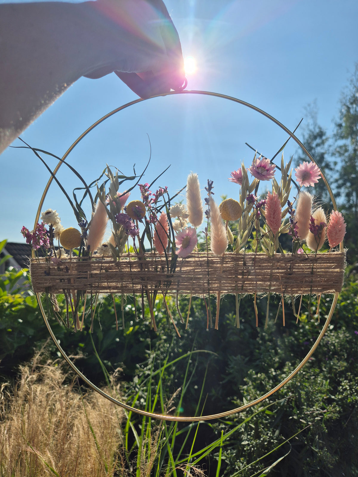 Dried flower hoop being held wit the summer blue skies in the background