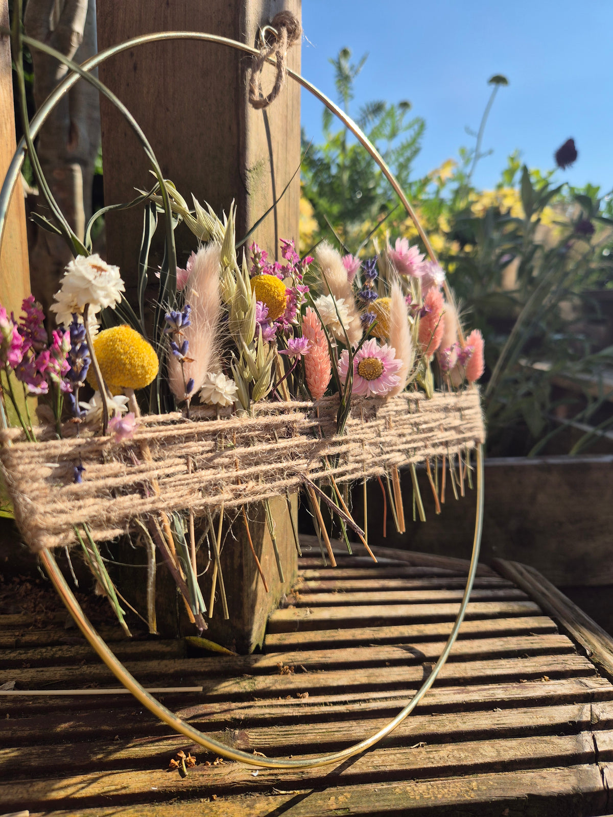 Summer inspired dried flower hoop with pink and peach flowers and a blue sky background